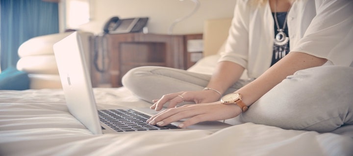 mulher sentada na cama mexendo no computador, empréstimo online, empréstimo pessoal online, refinanciamento, empréstimo para negativado, empréstimo barato