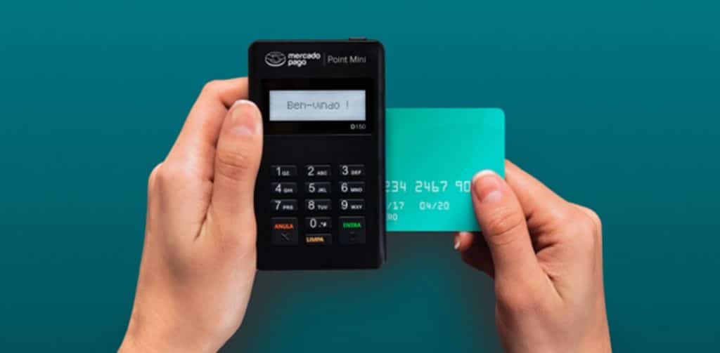 mãos segurando a máquina de cartão point mini enquanto faz uma transação com cartão de crédito