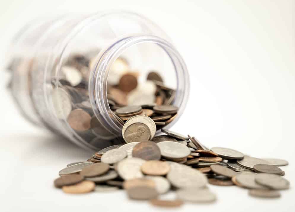 imagem de pote plástico tombado com moedas, em alusão a uma reserva de emergência