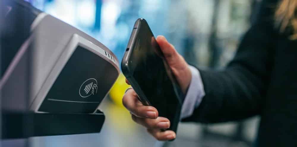 homem faz pagamento em fintech com celular, por meio de NFC e tecnologia
