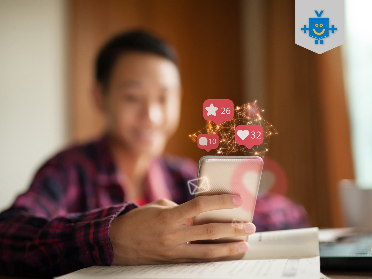 A imagem mostra uma pessoa sorrindo enquanto usa o celular, com ícones de redes sociais (curtidas, comentários e favoritos) flutuando sobre o aparelho.