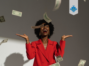 Mulher sorridente, de braços erguidos, vestindo um blazer vermelho, cercada por notas de dinheiro caindo do alto, representando a relação entre dinheiro e felicidade de forma leve e positiva.